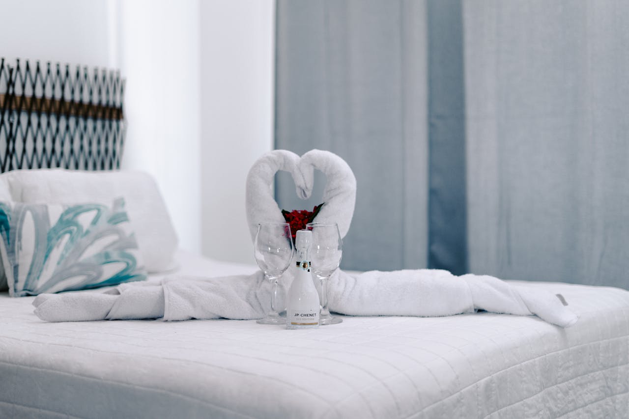 Elegant towel swans with champagne on bed, perfect romantic getaway decor.